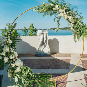 Modern Gold-Coated Round Wedding Arch on a brick patio overlooking an ocean view